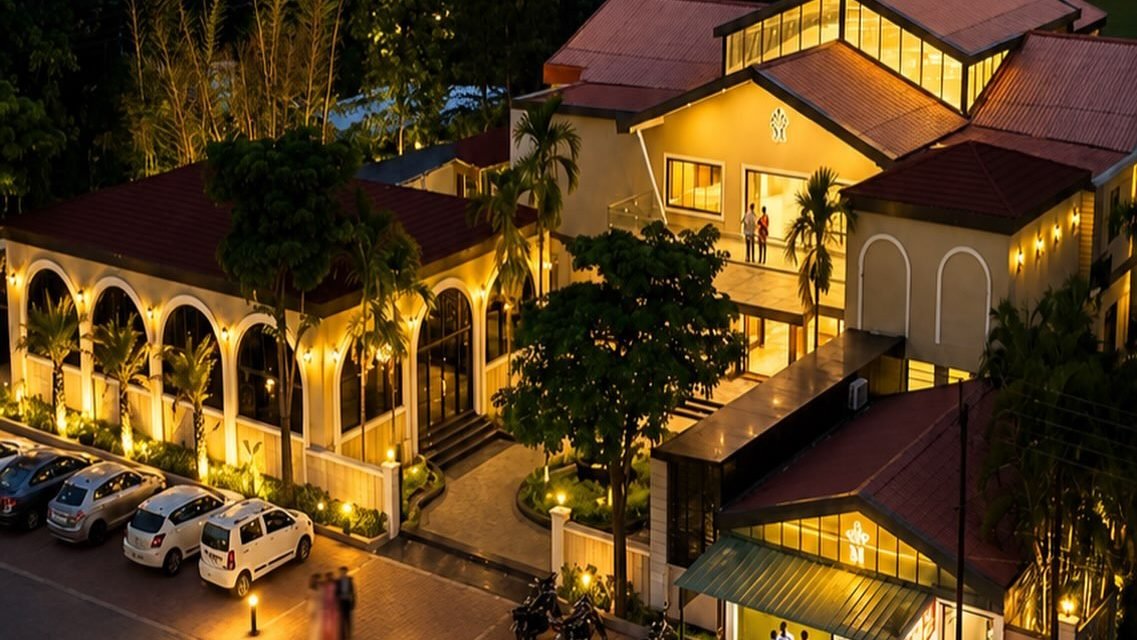 Meera Celebration lit up at dusk, seen from above — banquet hall, restaurant and lodging on one campus