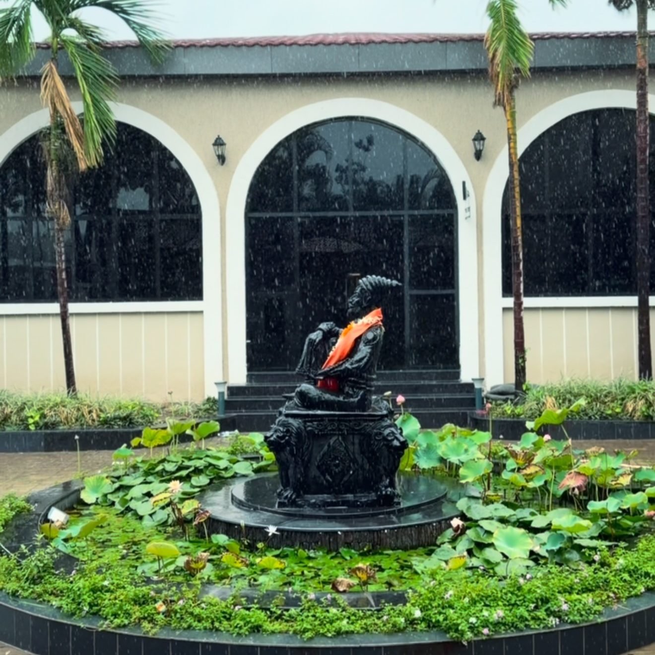 The arched frontage and lotus pond at Meera Celebration during the monsoon